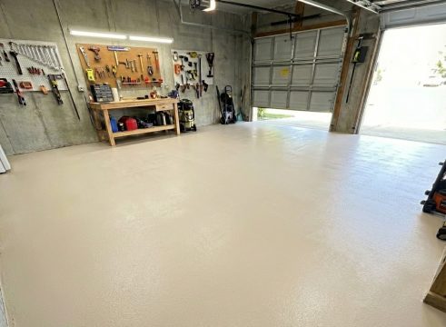 Garaż przydomowy zorganizowany przy ścianie z narzędziami i jasną posadzką w odcieniu RAL 1013